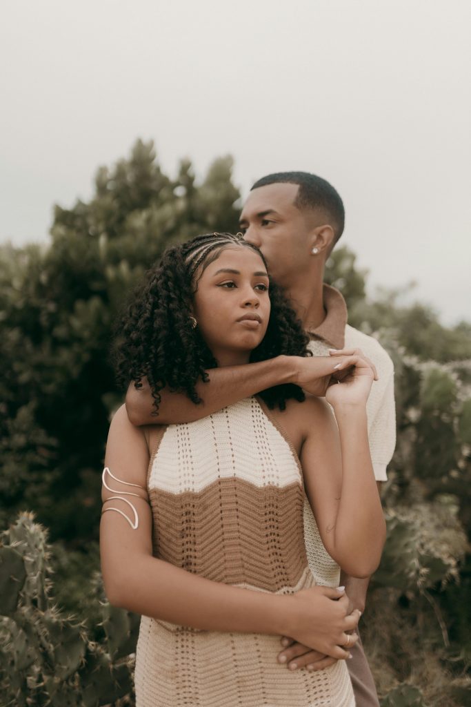 Serene portrait of an affectionate couple embracing amidst lush greenery outdoors.