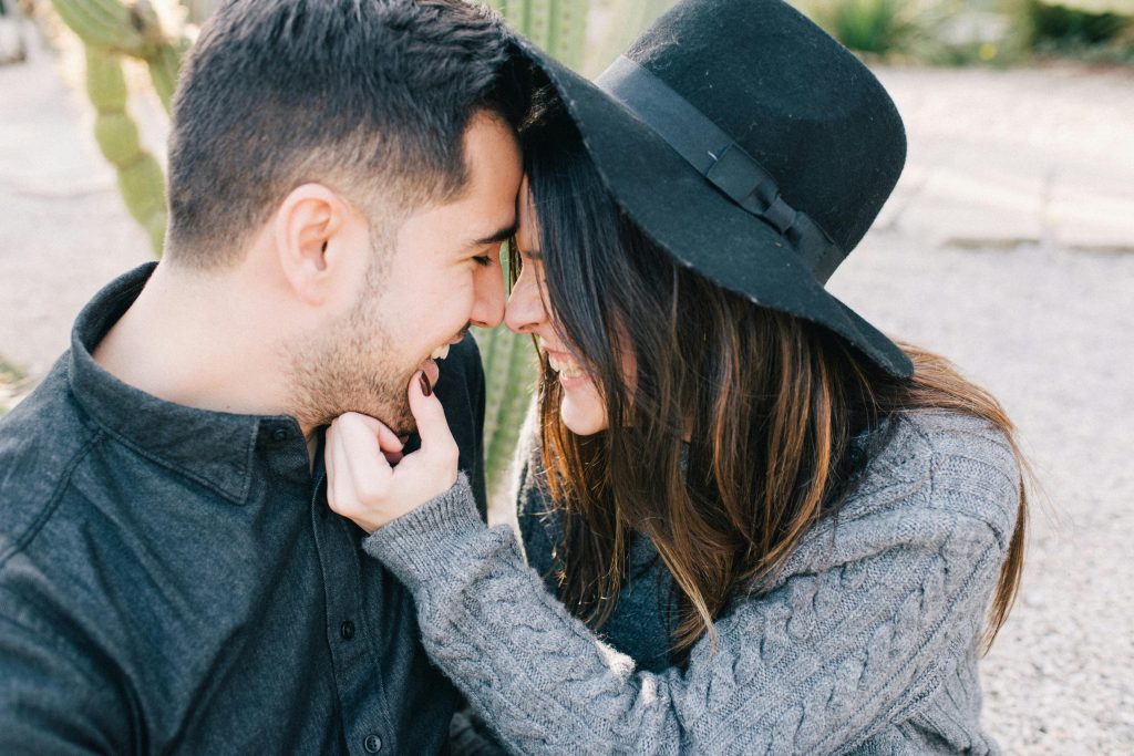A couple shares a tender, joyful moment outdoors with smiles and close connection.
